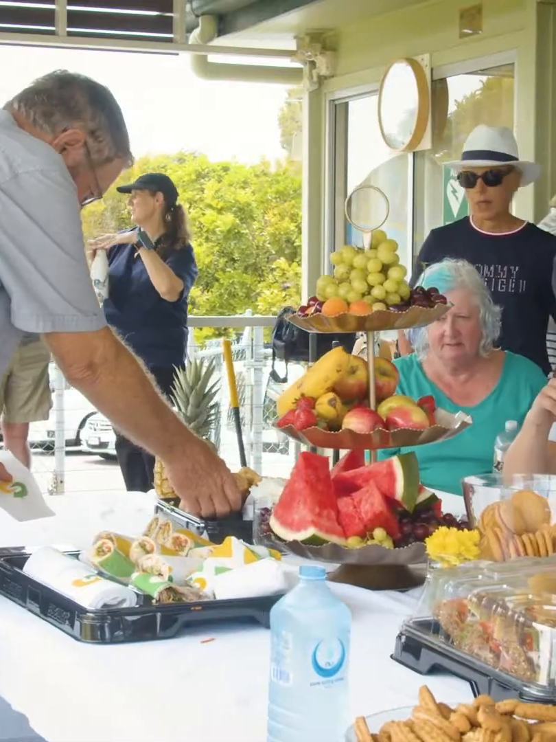 A table of fruit, sandwiches and a pineapple on a clubhouse verandah